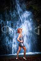 Rothaarige Frau vor einem Wasserfall