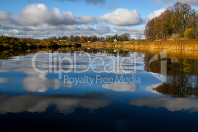 Autumn landscape with colorful trees, yellow grass and river. Re