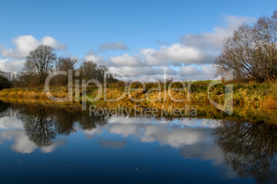 Autumn landscape with colorful trees, yellow grass and river. Re