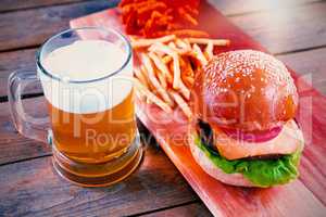 Beer mug, burger and fries on wooden table
