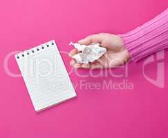 hand holding a white crumpled sheet of paper