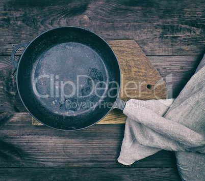 black round frying pan with wooden handle and gray linen kitche