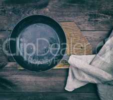black round frying pan with wooden handle and gray linen kitche