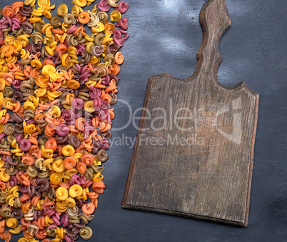 old empty wooden cutting board and unprepared fusilli pasta