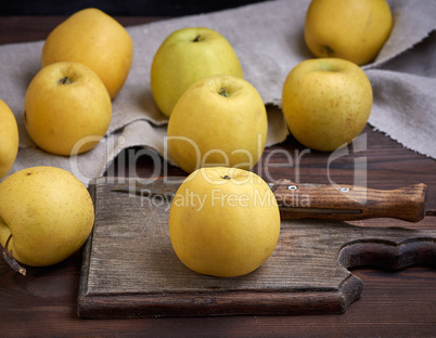 ripe whole yellow apples on a brown wooden board