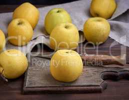 ripe whole yellow apples on a brown wooden board