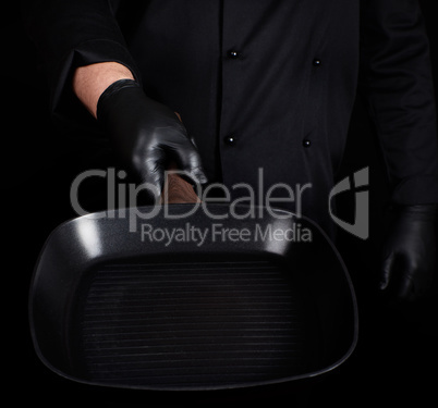 Chef in black uniform and black latex gloves holding an empty sq