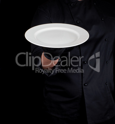 cook holds in his hand a round empty white plate