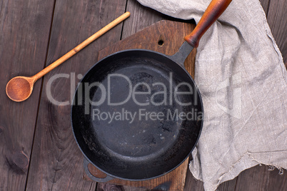 empty black round pan with wooden handle and wooden spoon