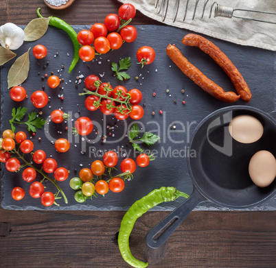 raw eggs in eggshell, fresh red cherry tomatoes and sausage