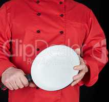 cook in red uniform holding an empty round white frying pan