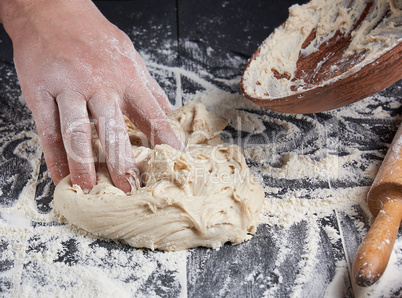 man's hands knead white wheat flour dough