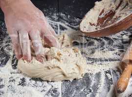 man's hands knead white wheat flour dough
