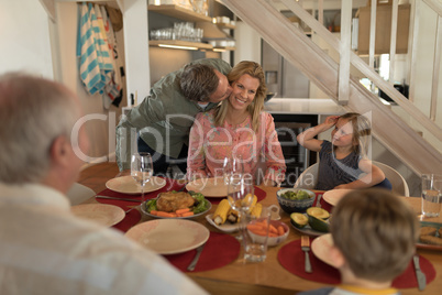 Man kissing his wife on dining table