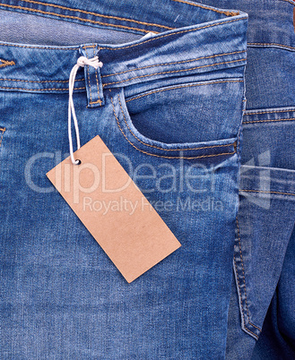 fragment of blue jeans with a brown paper empty tag