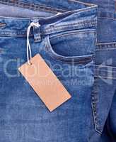 fragment of blue jeans with a brown paper empty tag