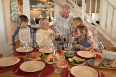 Senior man offering bouquet of flower to senior woman on dining table