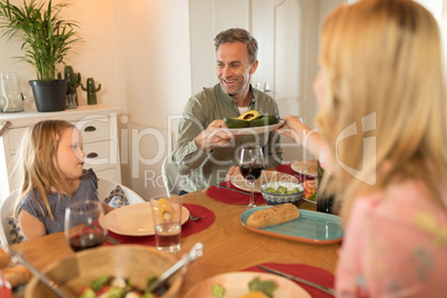 Woman passing food to man on dining table