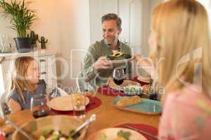 Woman passing food to man on dining table