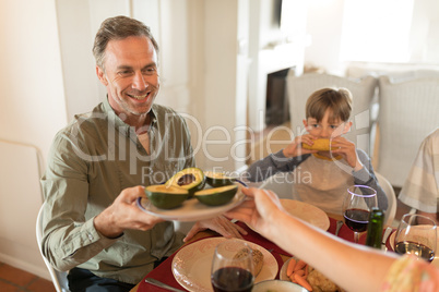 Woman passing food to man on dining table