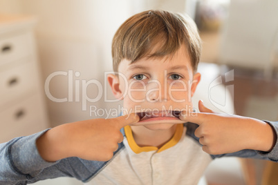 Boy stretching his mouth with his fingers at home
