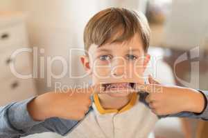 Boy stretching his mouth with his fingers at home