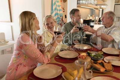 Family toasting glasses of wine on dining table