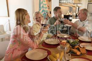 Family toasting glasses of wine on dining table