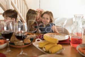 Mother kissing her daughter on dining table