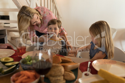 Mother wiping her sons mouth with napkin on dining table