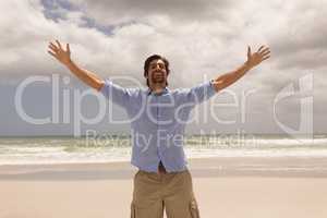 Man standing with arms outstretched on the beach