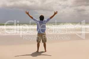 Man standing with arms outstretched on the beach