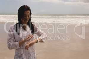 Young woman using smartwatch on beach
