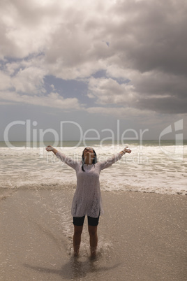 Young woman with arms stretched out standing on beach