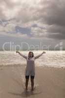 Young woman with arms stretched out standing on beach