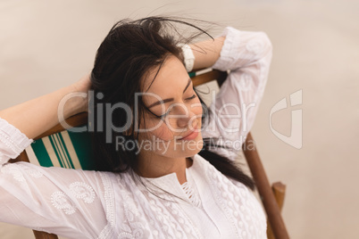 Young woman with eyes closed and hands behind head relaxing on sun lounger