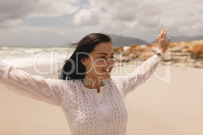 Happy young woman with arms stretched out standing on beach