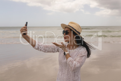 Young woman giving flying kiss while taking selfie with mobile phone