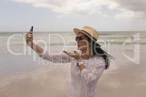 Young woman giving flying kiss while taking selfie with mobile phone