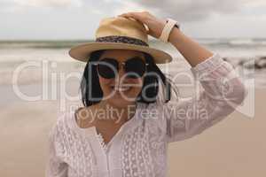 Young woman holding hat and looking at camera on beach