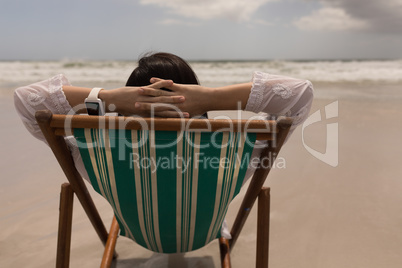 Young woman with hand behind head relaxing on sun lounger