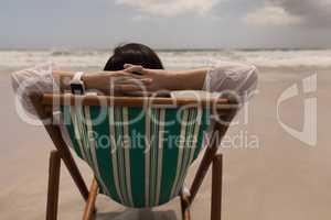 Young woman with hand behind head relaxing on sun lounger