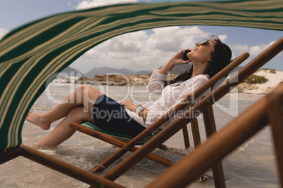 Young woman relaxing on sun lounger and talking on mobile phone