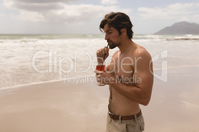 Young man drinking cocktail on beach