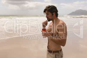 Young man drinking cocktail on beach