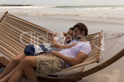Young couple relaxing on hammock at beach Young couple relaxing on hammock at beach