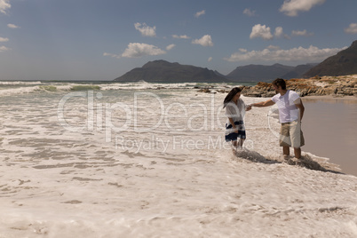 Young couple holding hands and having fun at beach