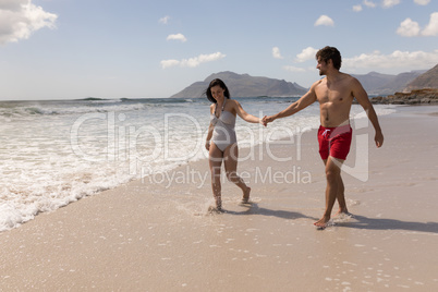 Young couple holding hands and having fun at beach