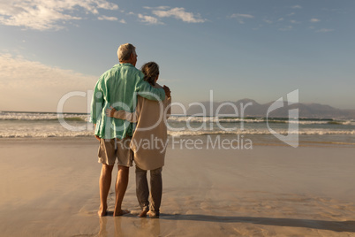 Senior couple standing together arm around on the beach