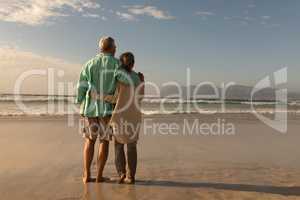 Senior couple standing together arm around on the beach